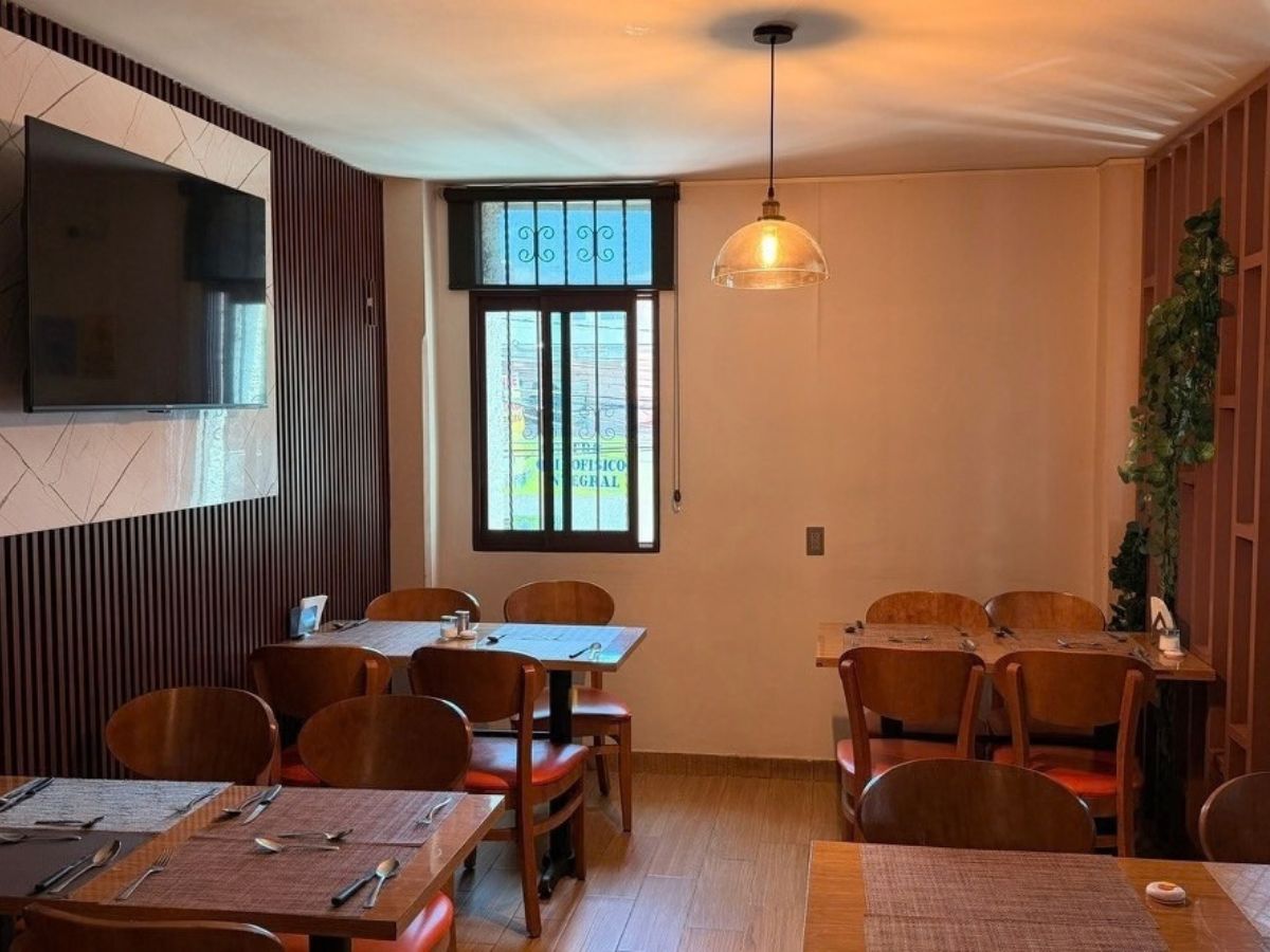 Área de mesas con pantalla y lámpara colgante en Restaurante El Yoyo
