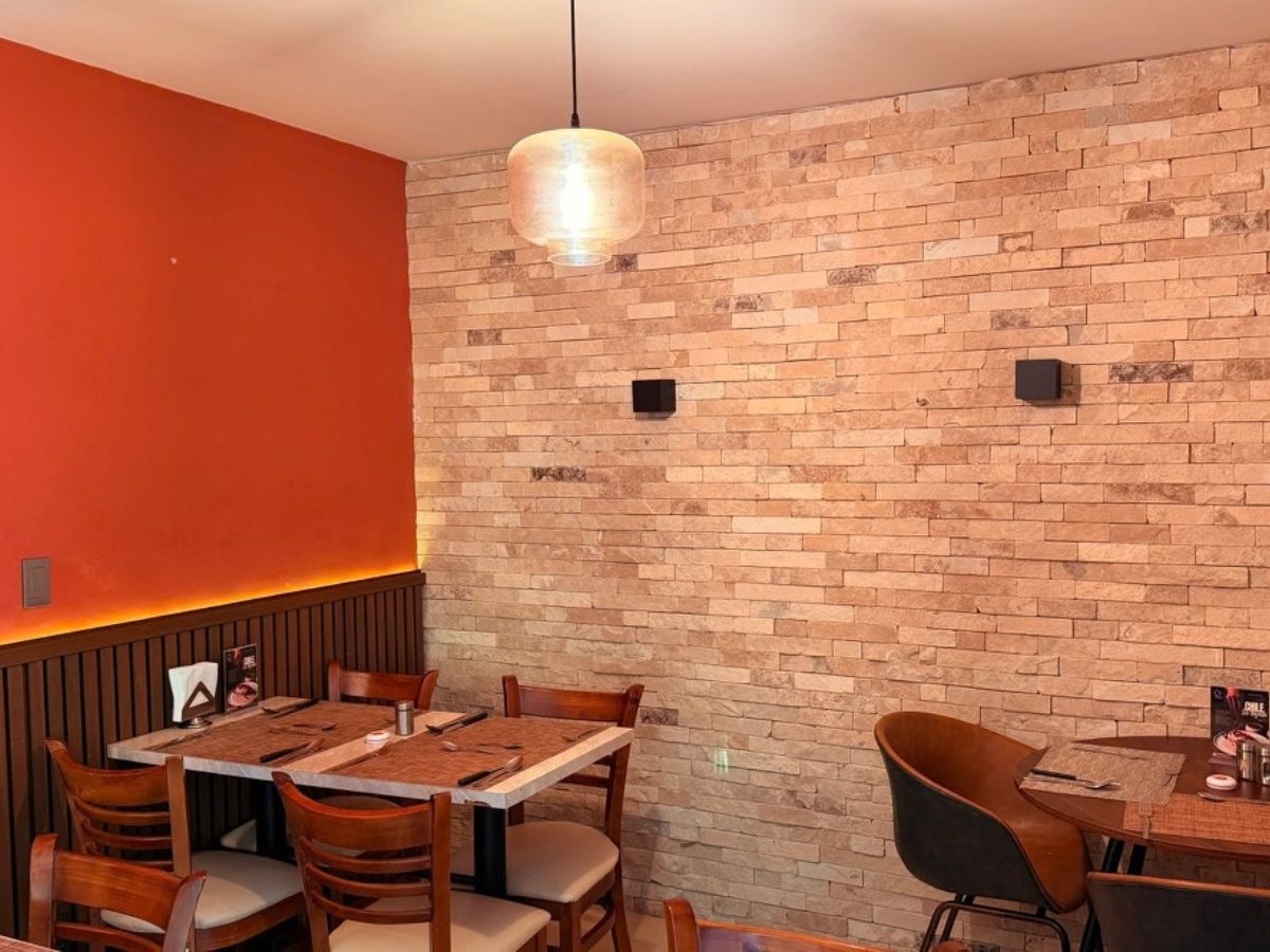 Rincón con pared de piedra y muro naranja en El Yoyo